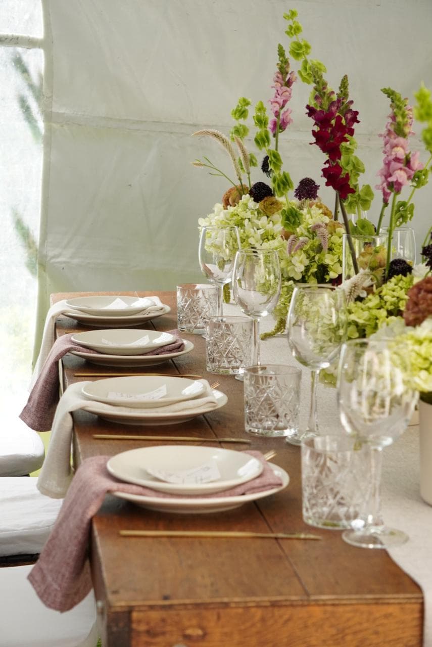 Mesa larga con flores, vajilla y textiles