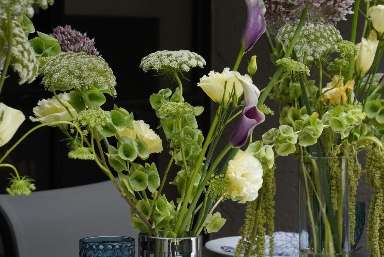 Arreglo floral verde y lila en una mesa